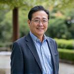 編集長、伝統的な庭園を背景にした穏やかな笑顔の男性